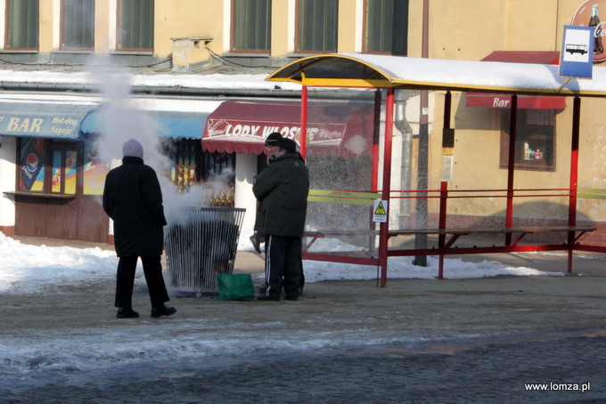 osoby czekające na autobus już ogrzewają się przy koksowniku